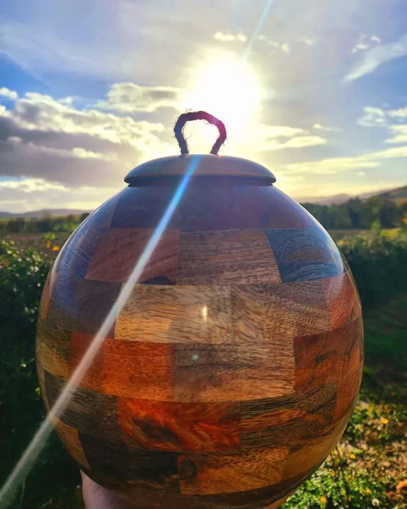 Urne funéraire artisanale en bois mosaïque exposée au soleil en extérieur