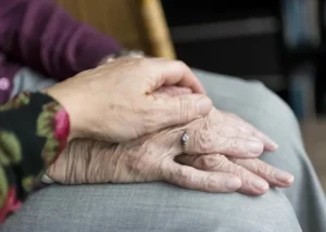 Gros plan sur deux mains séniors enlacées avec une alliance en signe de soutien et de prévoyance