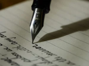 Gros plan sur la plume d'un stylo-plume écrivant de la calligraphie sur du papier ligné