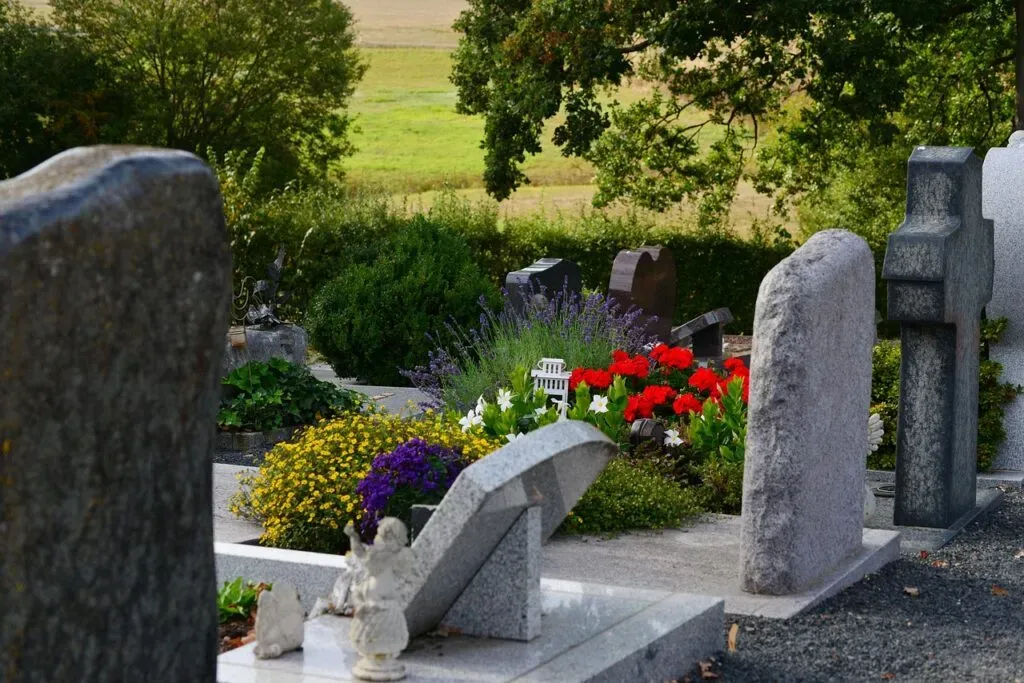 Tombes et pierres tombales en granit ornées de fleurs colorées dans un cimetière paysager
